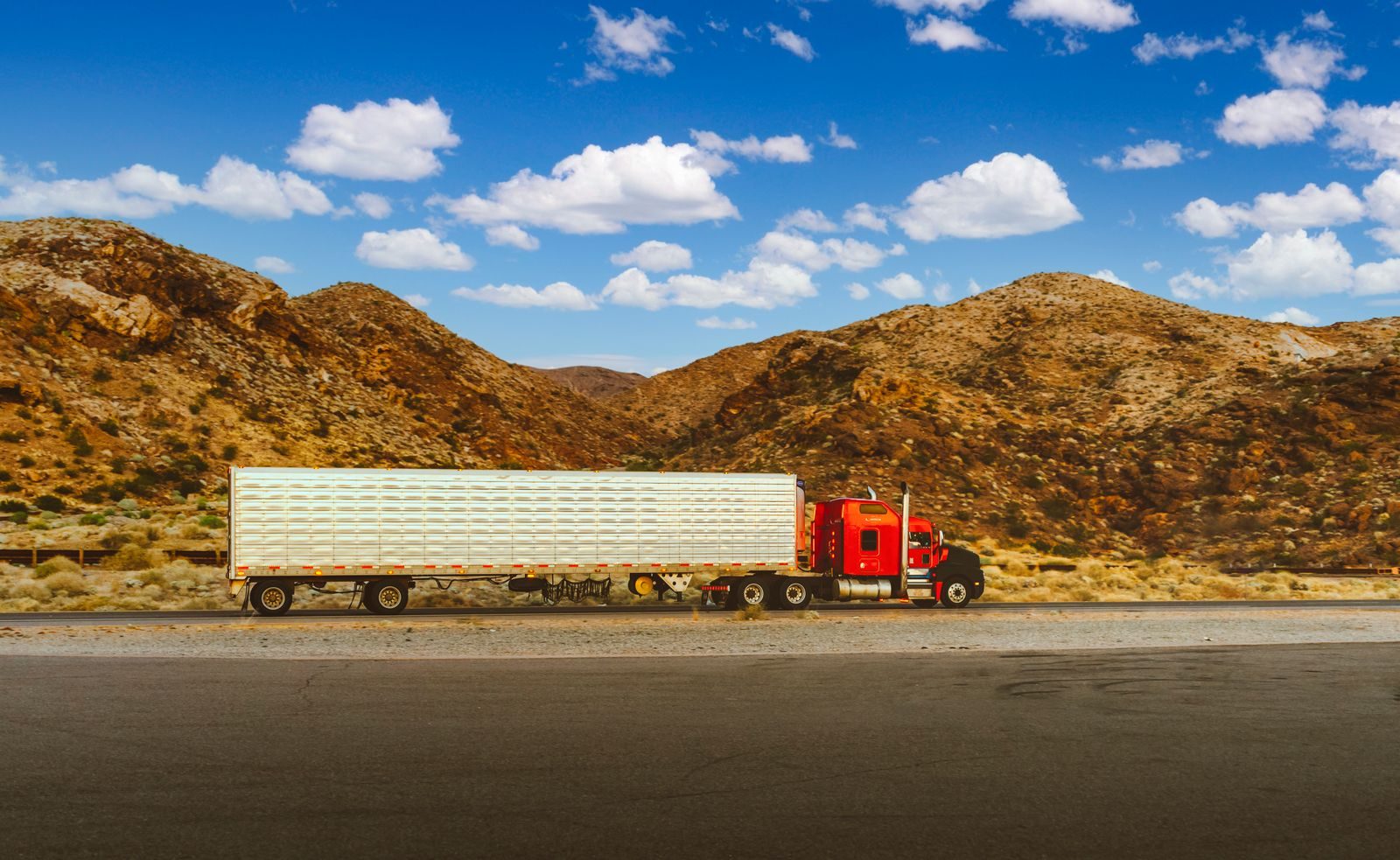 A tractor-trailer moving along an open highway at golden hour